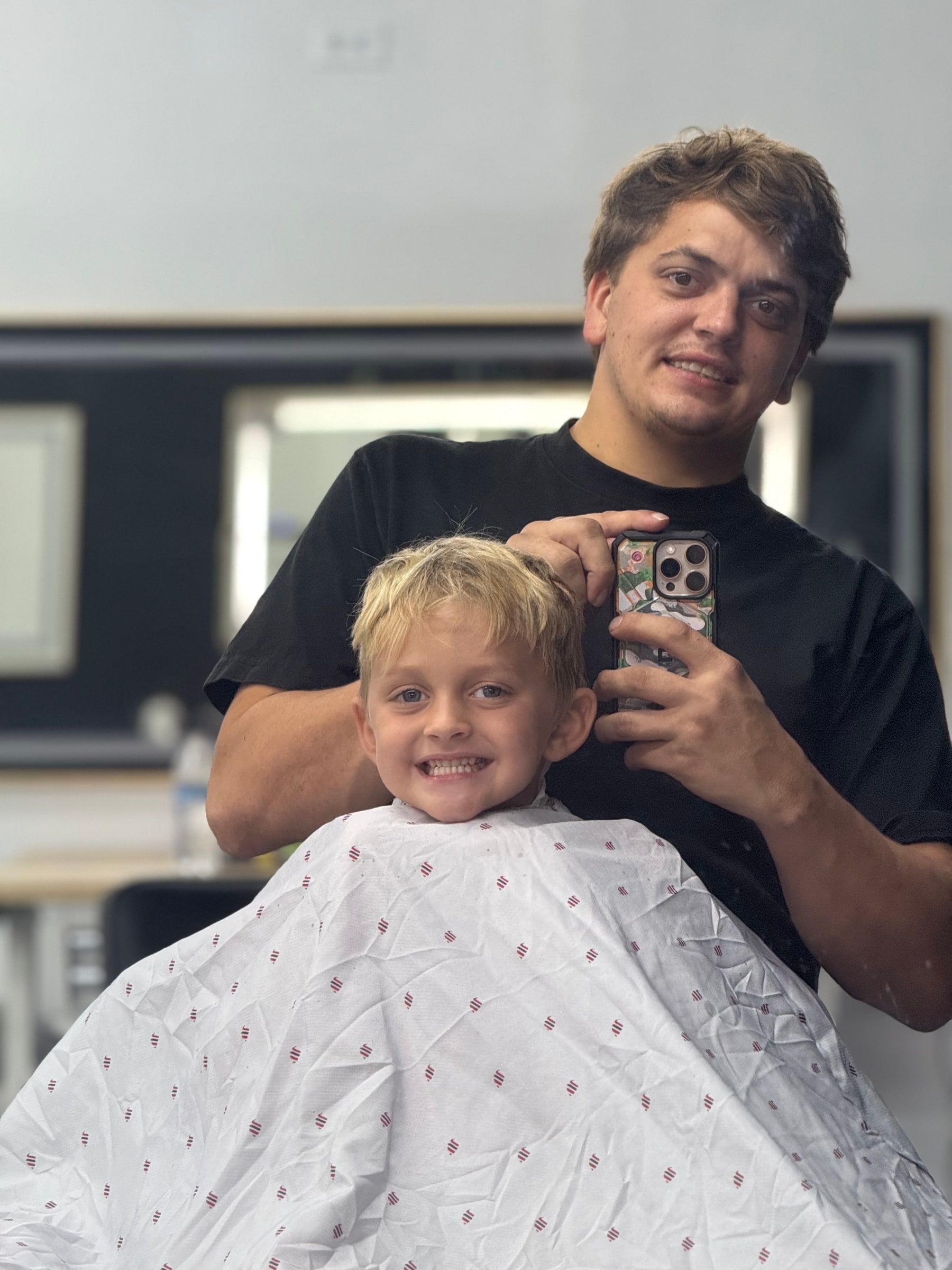Sage The Barber smiling with a young client after a haircut in Stuart